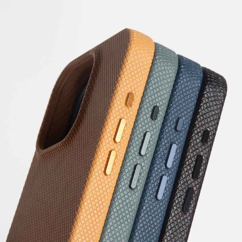 Four textured phone cases in brown, yellow, light blue, and dark blue are lined up, showing the side buttons and camera cutouts against a plain background.