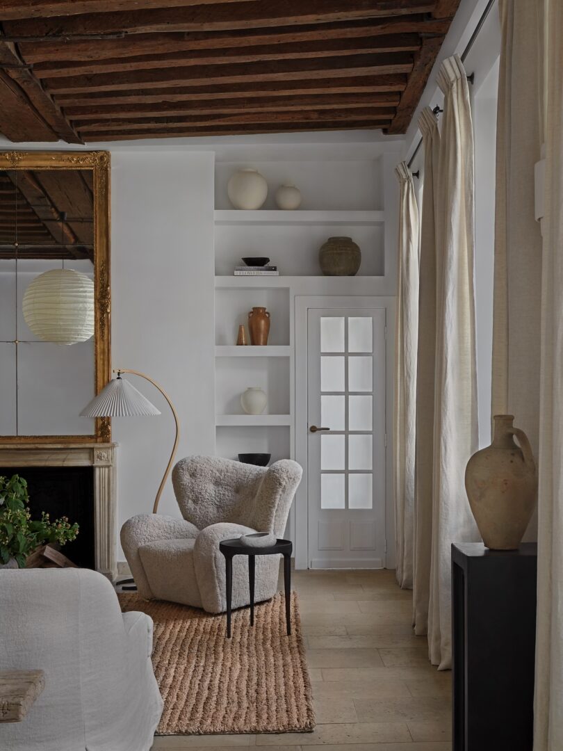 A corner of the living room, featuring a sculptural armchair, a jute rug, and a floor lamp