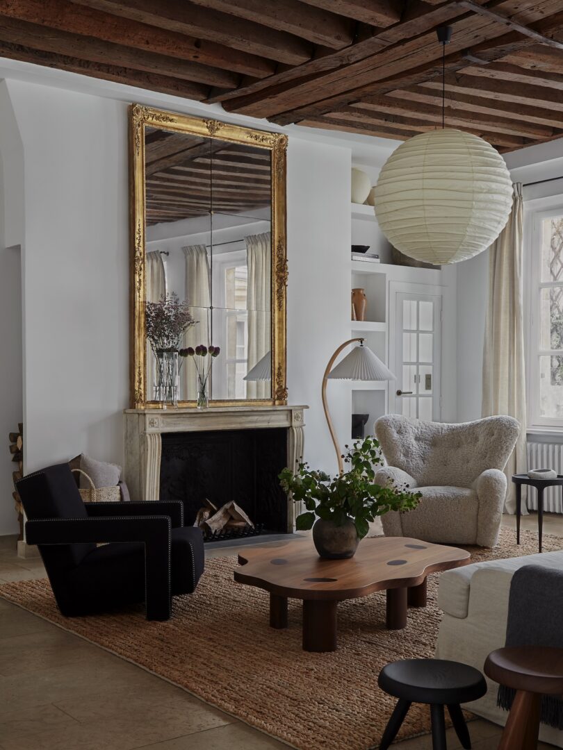 A Parisian living room featuring a grand, gilded mirror above a fireplace