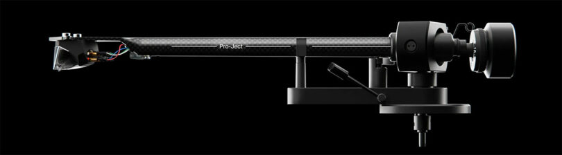 Close-up of a Pro-Ject Debut EVO 2 turntable tonearm against a black background, showing intricate details and a sleek, modern design.