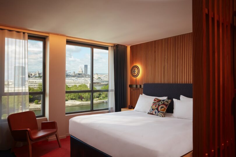 A tastefully furnished hotel room at SO/Paris, with expansive windows offering panoramic views of Paris landmarks