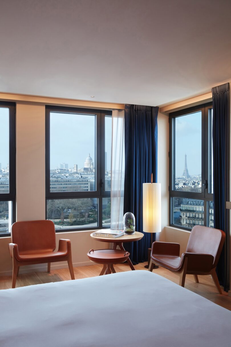 A bright and airy hotel room at SO/Paris, featuring modern furnishings and a stunning view of the Eiffel Tower