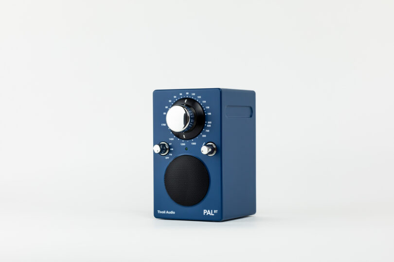 A blue, rectangular tabletop radio featuring a large tuning dial, volume and input knobs, and a speaker grille. The brand "Tivoli Audio" and model "PAL BT" are labeled on the front.