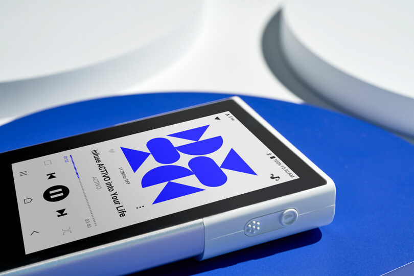 The Astell&Kern P1 digital music player, featuring a blue abstract design on the screen, elegantly rests on a blue and white surface.