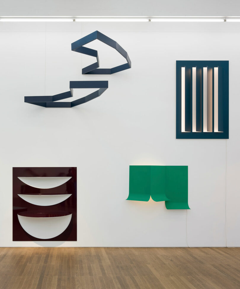 A gallery wall displaying abstract geometric light sculptures in various shapes and colors