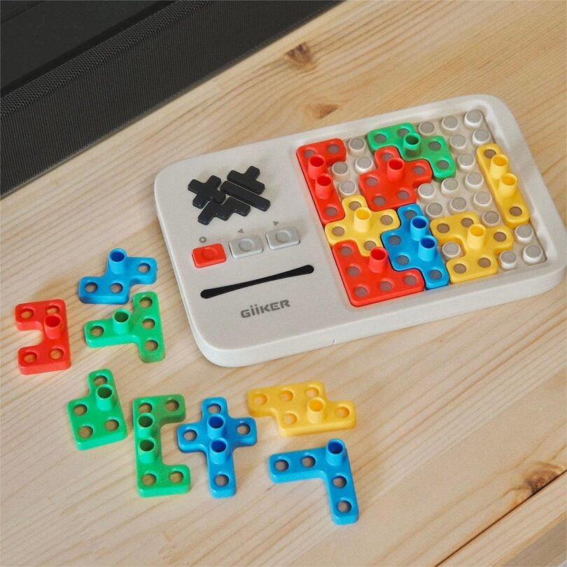 Puzzle game with colorful Tetris-shaped pieces on a wooden table beside the game board