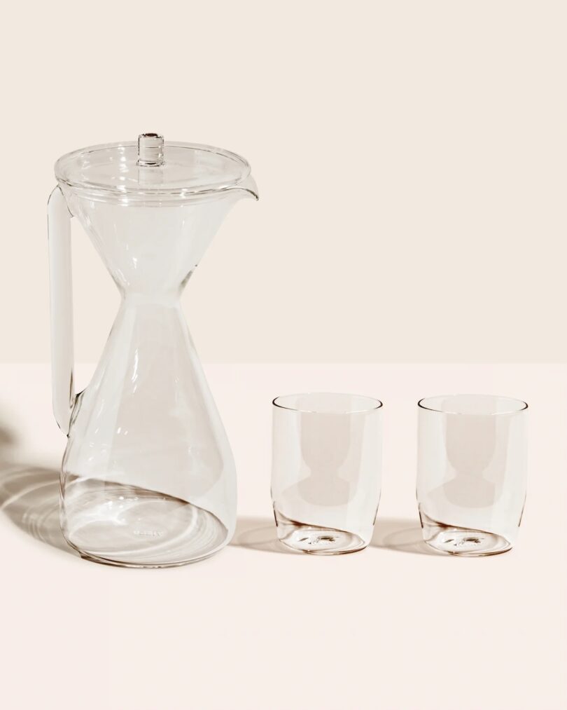 A clear carafe next to two clear double-walled glasses