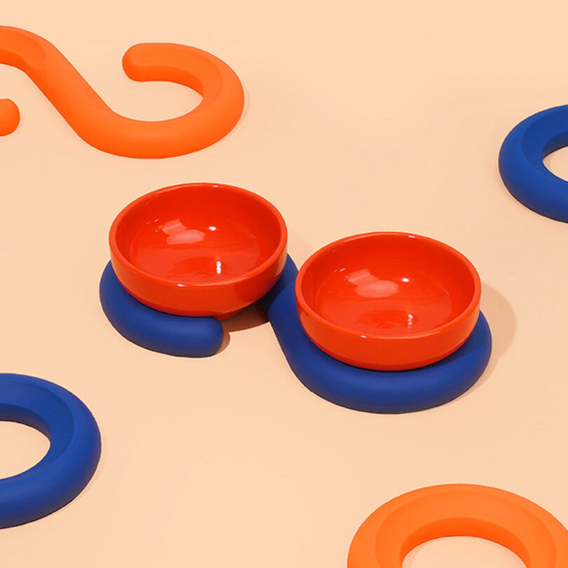 two red ceramic bowls on a blue silicone spiral base