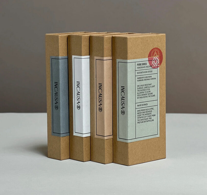 Four brown cardboard incense boxes stand upright on a gray surface. Each box features the Incausa logo and a vertical colored label. A red circular emblem is on the rightmost box.