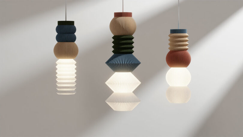 Three STAK Modular Lamps with geometric designs in various colors hang elegantly against a plain background.