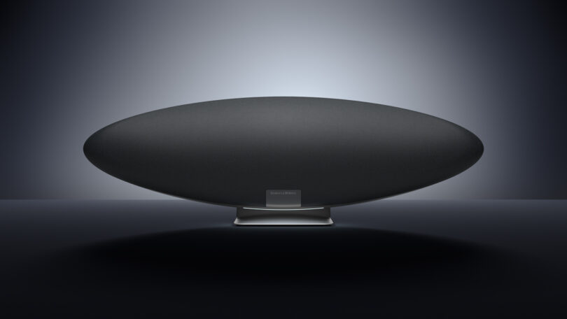 A black, oval-shaped speaker, the Zeppelin Pro Edition, rests elegantly on a dark surface with a centered light source illuminating the background.