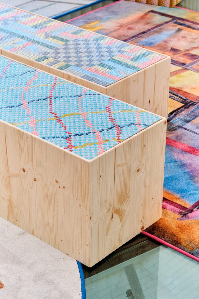 Wooden benches with colorful, geometric-patterned cushions, placed on a vibrant, multi-colored carpet