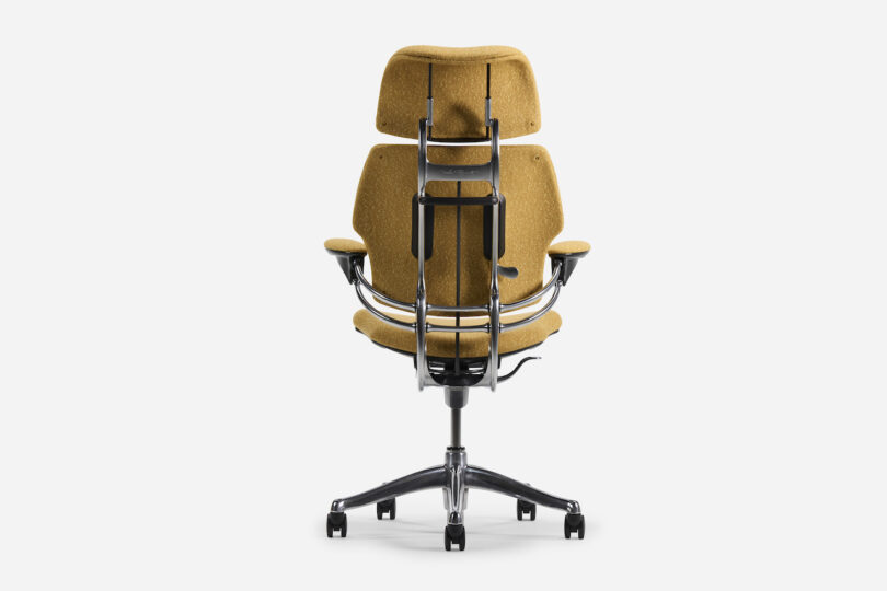 Office chair with mustard yellow upholstery, ergonomic design, adjustable armrests, and a headrest on a five-wheel base