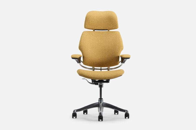 Office chair with mustard yellow upholstery, ergonomic design, adjustable armrests, and a headrest on a five-wheel base