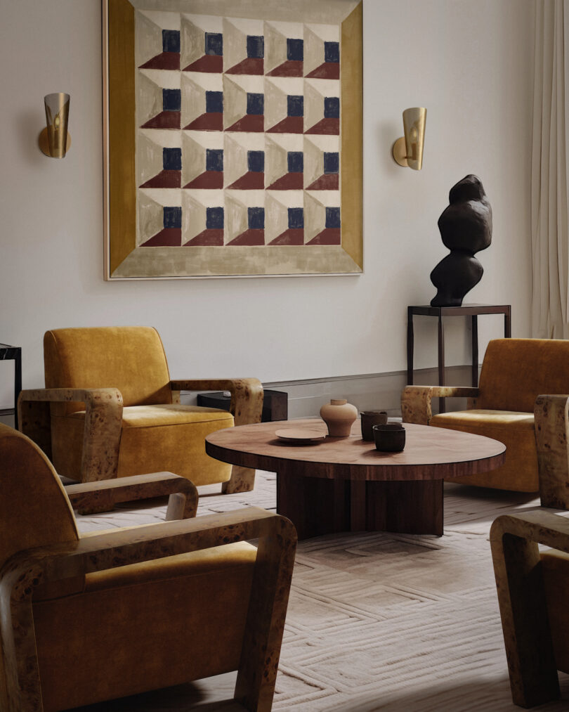 A living room with four mustard armchairs, a round wooden table, geometric wall art, and sculptures