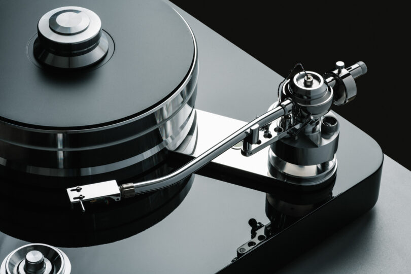 Close-up of a high-end turntable with a sleek, metallic tonearm and a black glossy base.