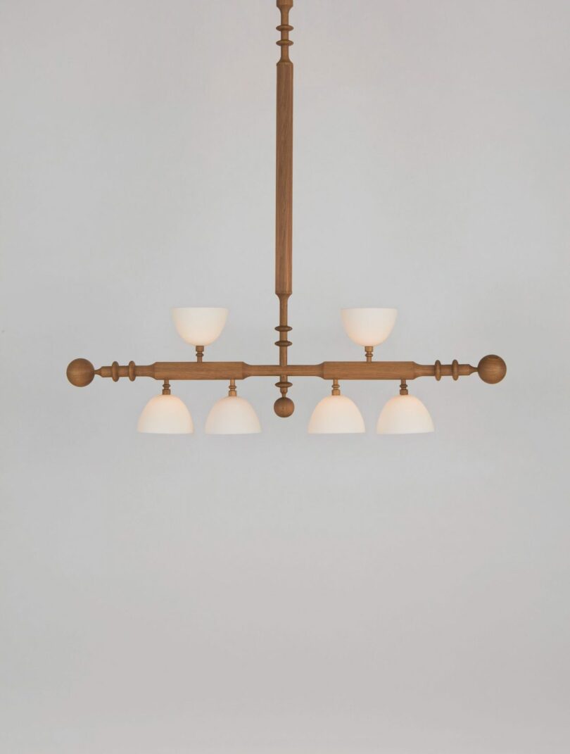 A wooden chandelier with six frosted glass lampshades arranged in two rows against a plain background