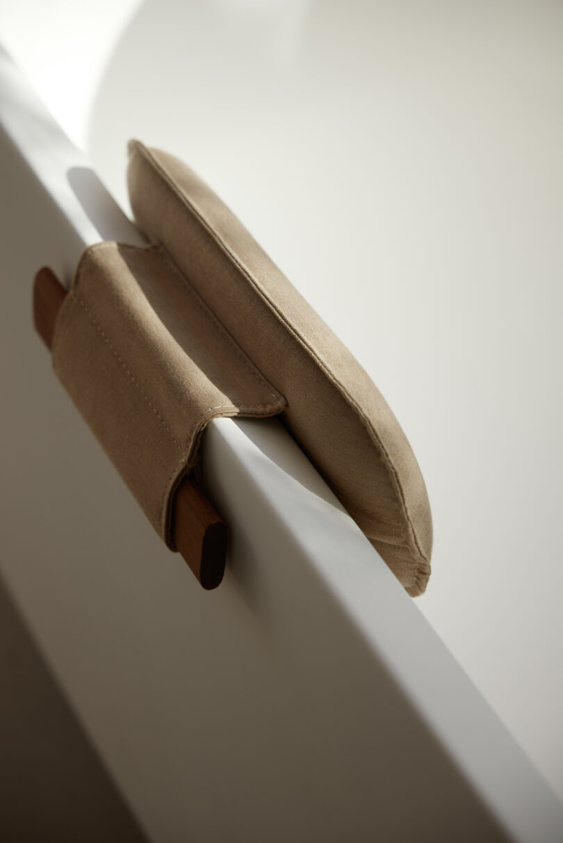 Beige bath pillow resting on the edge of a white bathtub