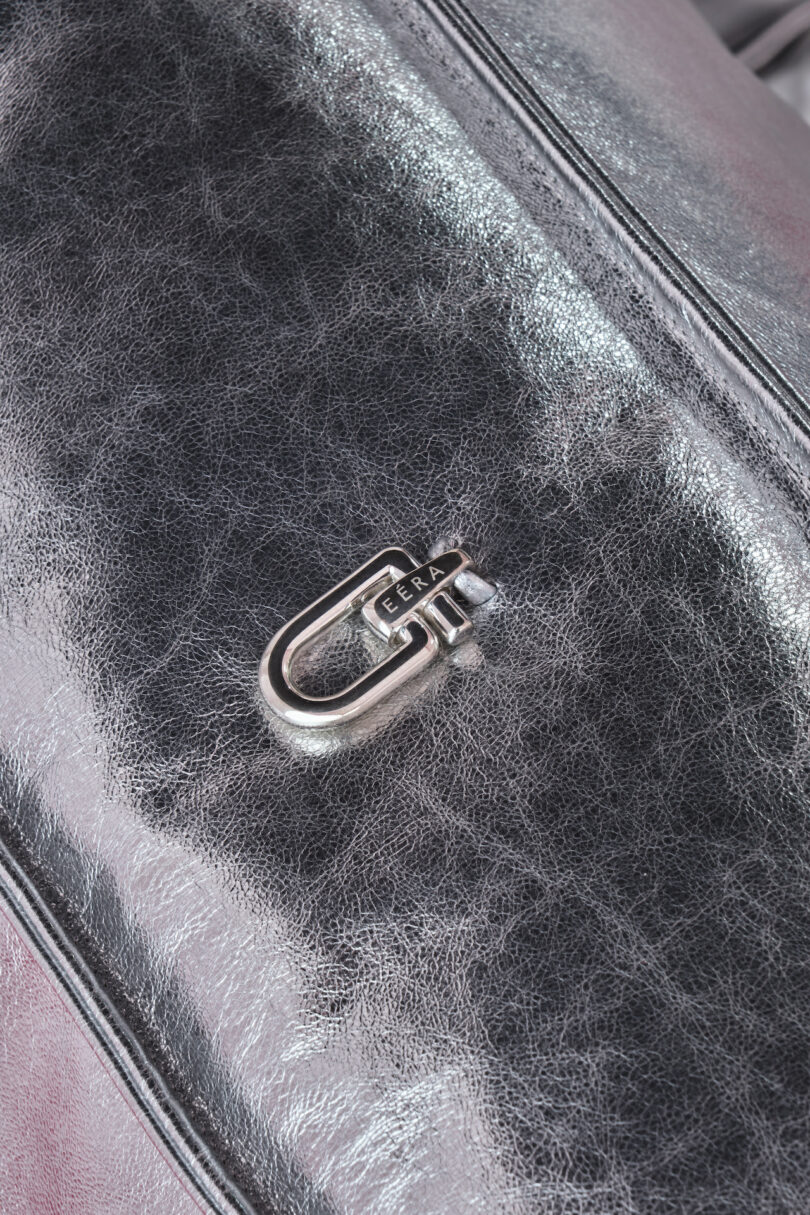 Close-up of a metallic silver leather chair with a shiny clasp engraved with the word "EERA.