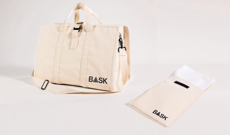 The BASK Bag from two-point is a beige tote with multiple pockets, featuring handles and a shoulder strap. It’s perfectly displayed alongside a matching smaller pouch.