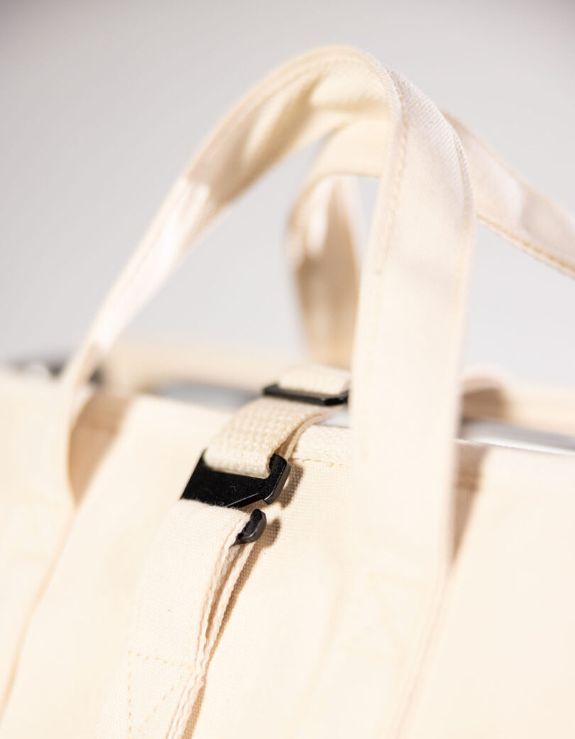 Close-up of a beige bag, featuring a sleek metal buckle.