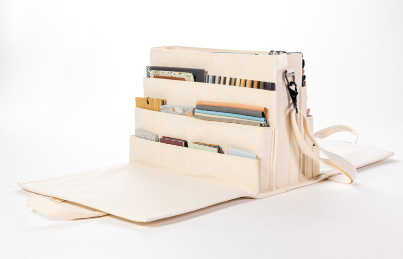 Cream-colored open organizer with multiple pockets holding various notebooks and papers, displayed on a white surface.