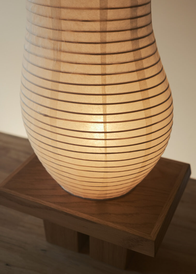 A paper lantern in a bulbous shape with horizontal stripes is placed on a wooden surface.