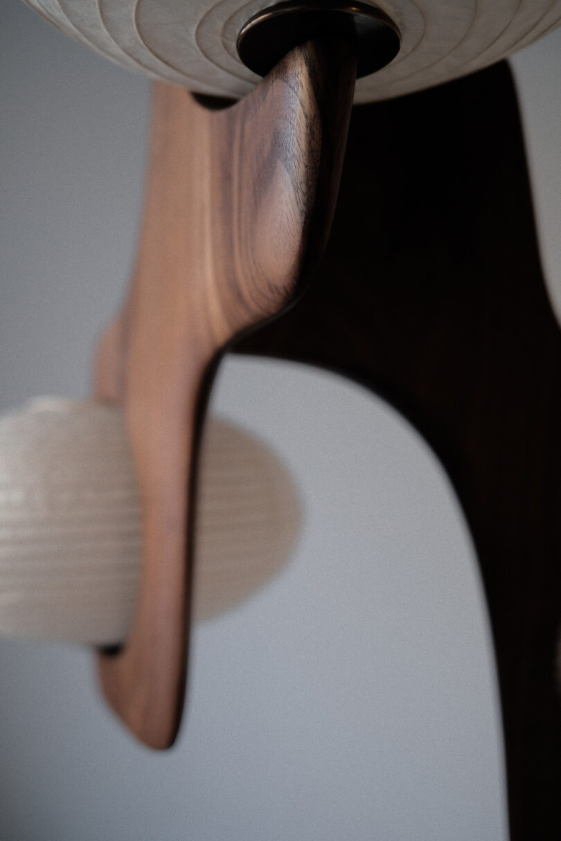 Close-up of a wooden chair frame and a textured white cushion, highlighting the grain and shape of the wood.