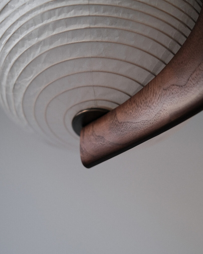 Close-up view of a round paper lantern with wooden frame against a neutral background.