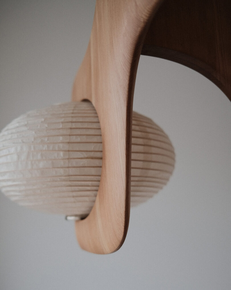 Close-up of a wooden pendant light fixture with a textured, oval-shaped paper lampshade.