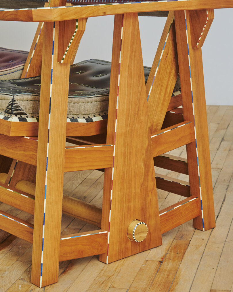 Wooden furniture with detailed inlays and patterned upholstery on a hardwood floor.