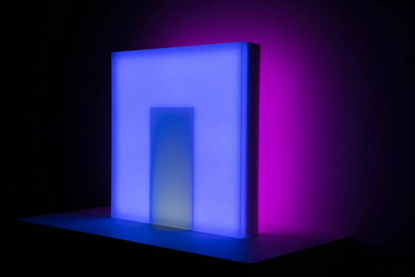 Anya Molyviatis's glowing rectangular sculpture features a stunning interplay of soft blue and pink illumination against a dark background.