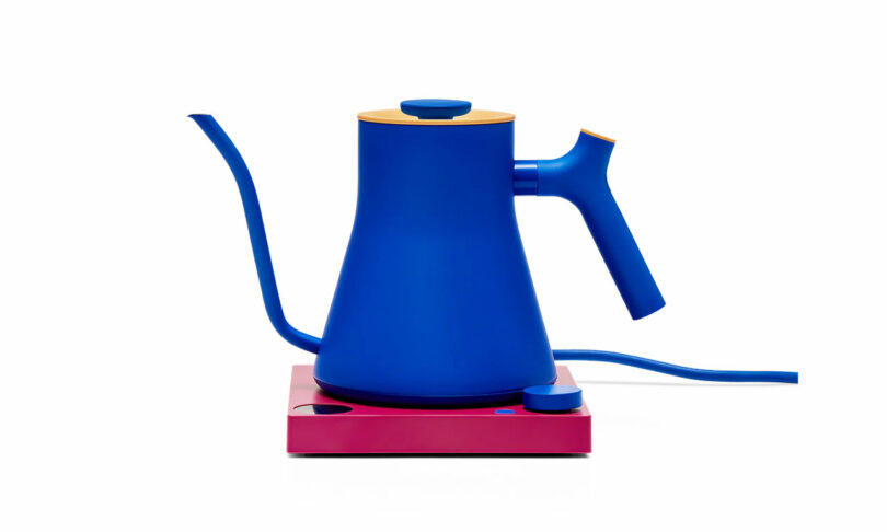 Electric kettle with a blue body, gooseneck spout, pink base, and yellow accents.