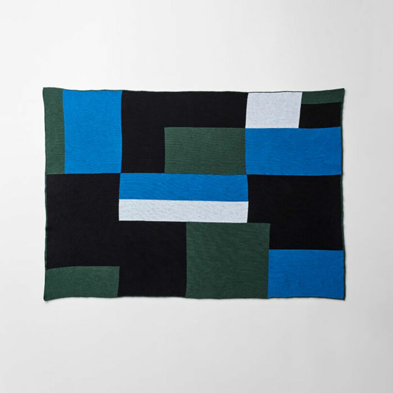 A rectangular textile designed as a modern gift, featuring a geometric pattern of black, green, blue, and white rectangles on a crisp white background.