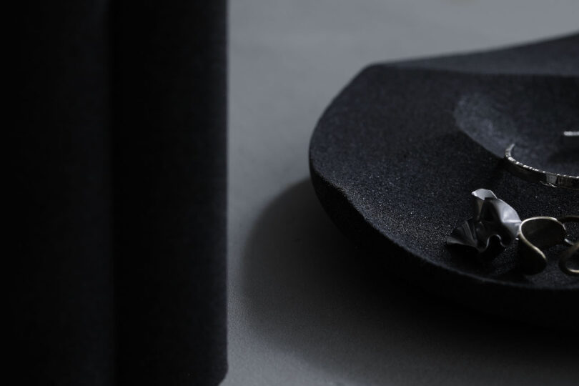 Minimalist black plate with silver jewelry on a dark surface.