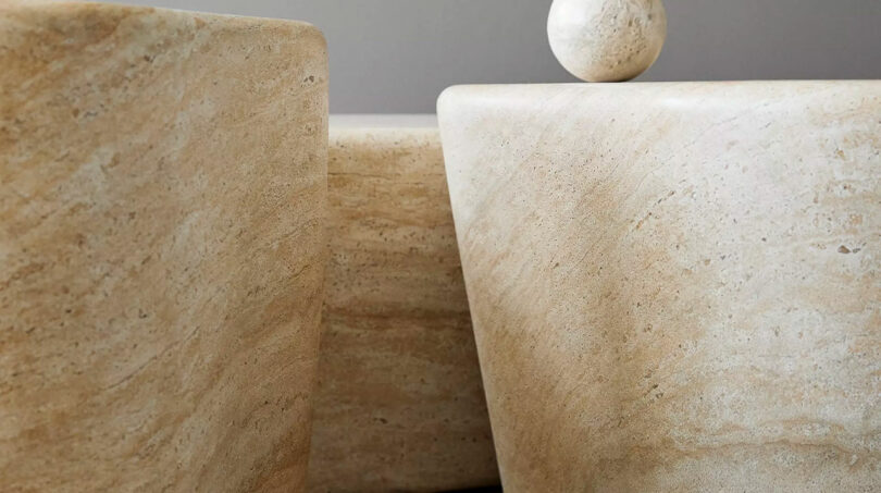 Close-up of stone slabs with a polished spherical object on top, displaying textured beige surfaces