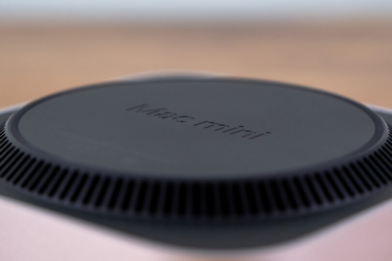 Close-up of the top of a Mac mini, displaying its engraved name and circular vent design.