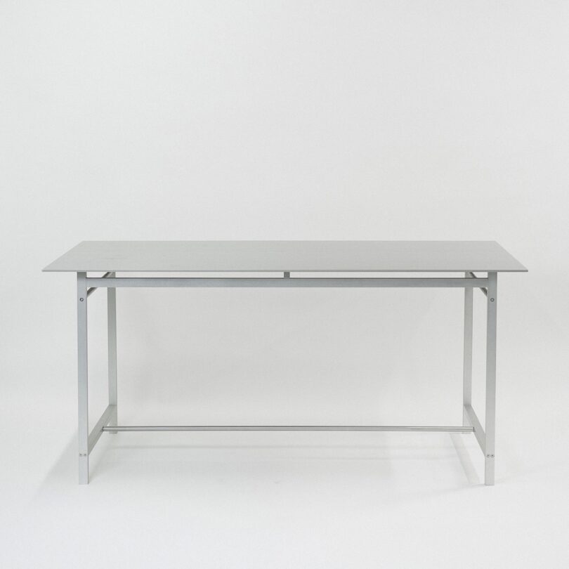 A minimalist gray metal desk with a flat rectangular surface and a simple, linear frame design.