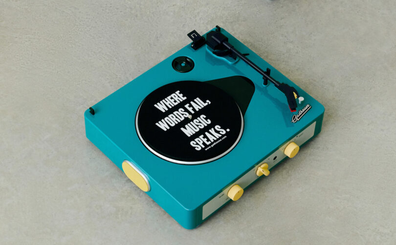 A turquoise record player with a black sticker on the platter reads, "Where words fail, music speaks.