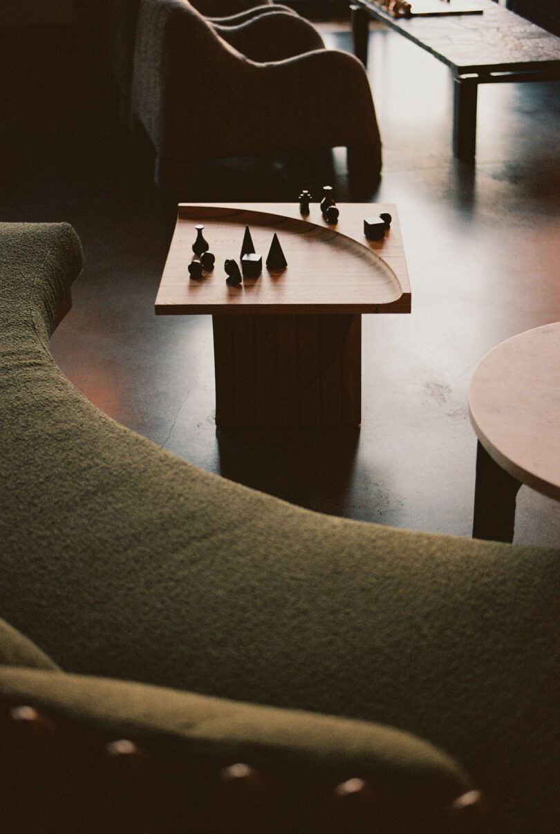 A modern lounge with curved seating, a square coffee table displaying small decorative objects, and soft lighting