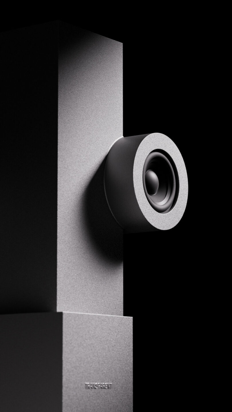 A close-up of a black speaker on a rectangular stand with a minimalist design against a dark background.