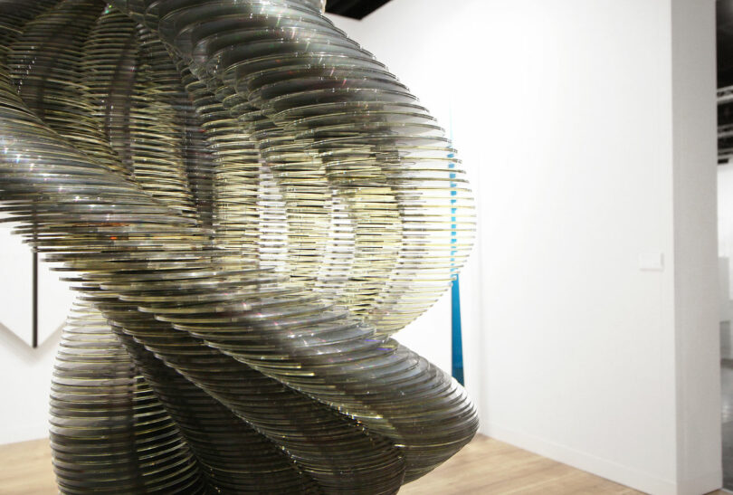 A spiraling stack of CDs gives view to a blue sculpture behind.