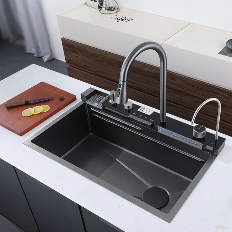 Modern kitchen sink with a sleek faucet, cutting board with sliced lemon, and a glass on the countertop.