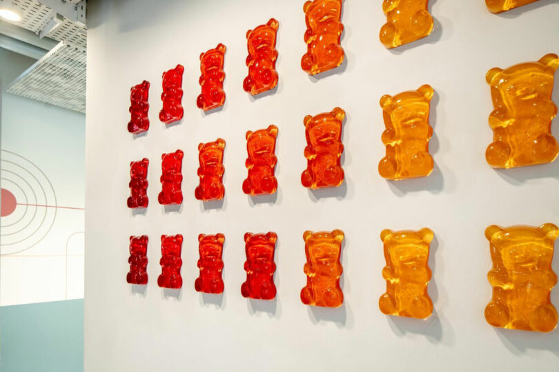 Wall art of large gummy bears in rows of red and orange hues.