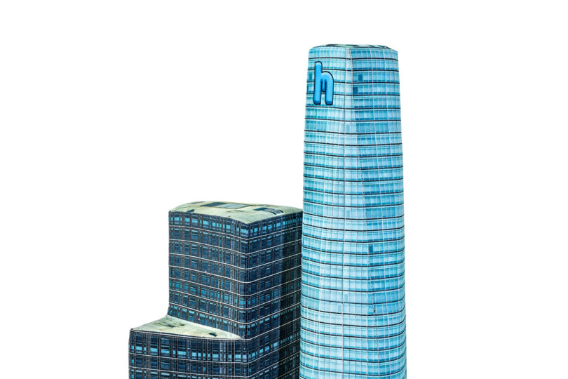 Two modern skyscrapers with grid-patterned facades, one taller with a rounded top and the other shorter with a flat top, isolated against a white background.