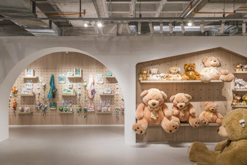 A store display featuring plush teddy bears on shelves with various toys artfully arranged on a pegboard wall.