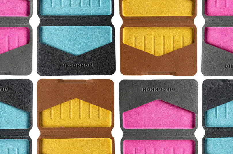 Colorful, geometric-patterned cases are arranged in a grid. The cases have teal, pink, and yellow interiors with "DISCOMMON" embossed on the black and brown exteriors.