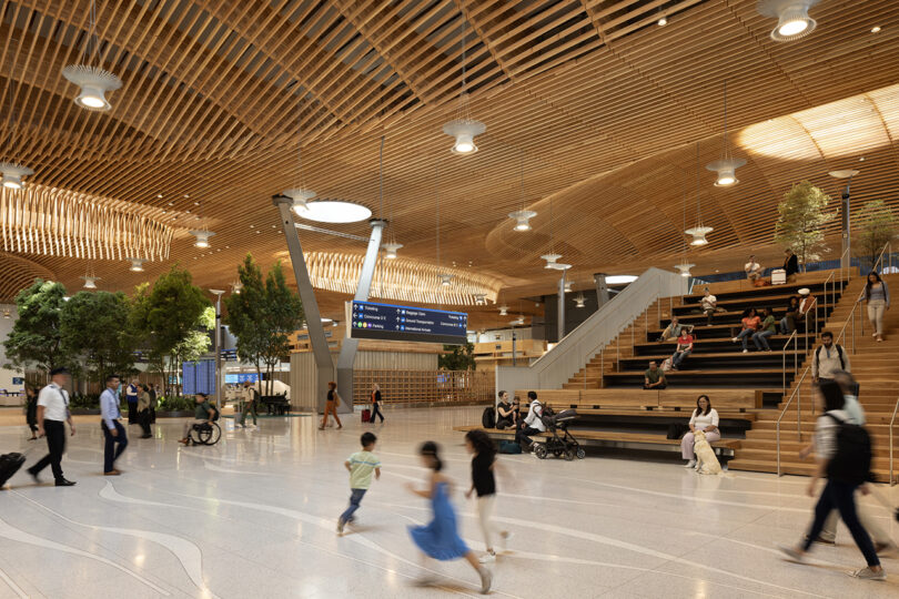 Le terminal de l'aéroport conçu par ZGF dispose de plafonds en bois, d'arbres luxuriants et de nombreux sièges. Pendant que les voyageurs se promènent et se détendent sur les marches, un panneau numérique suspendu au-dessus tient tout le monde informé.