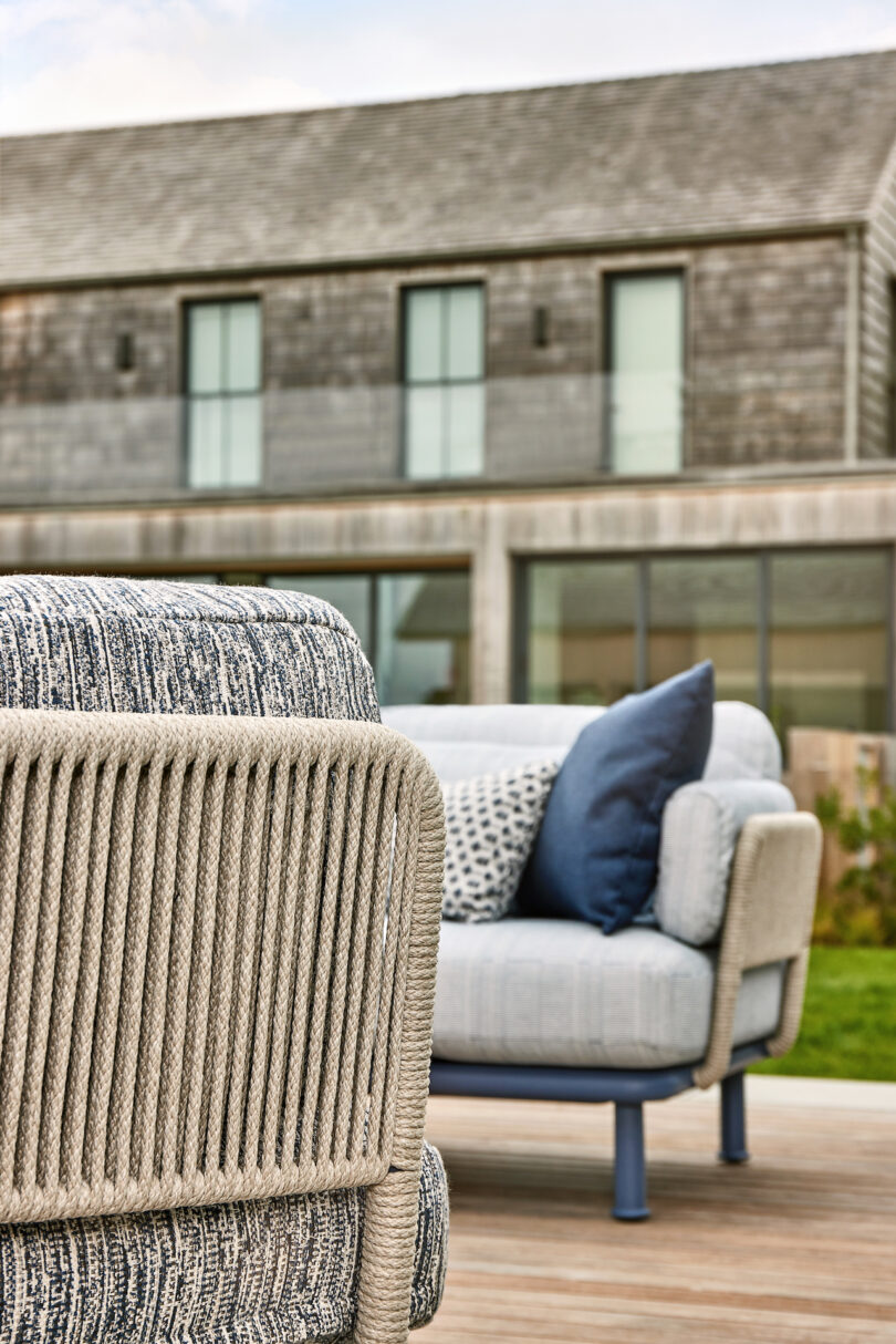 Outdoor seating with cushioned chairs on a wooden deck, set against a background of a modern building with large windows