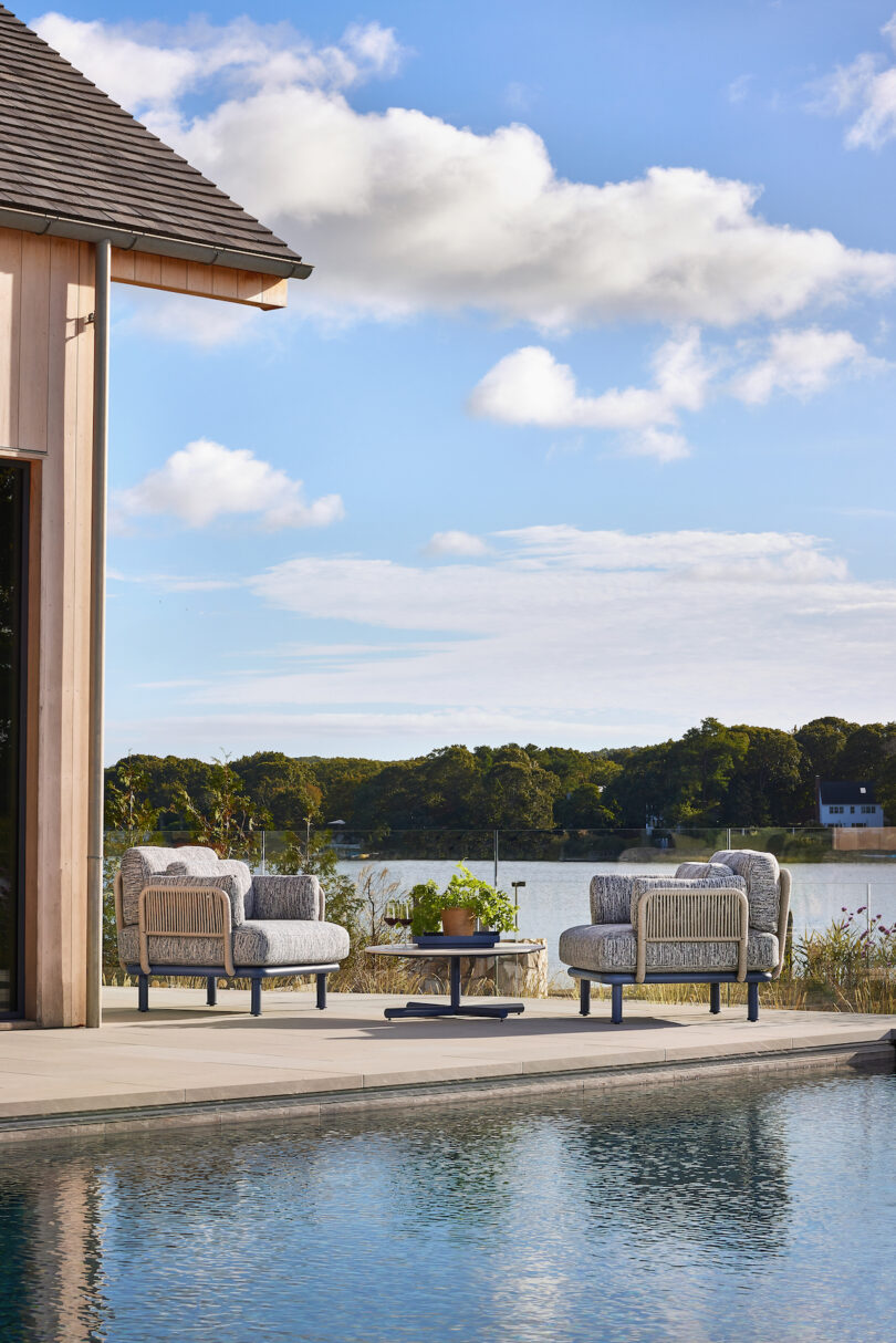 Outdoor seating area by a pool with two chairs and a table, overlooking a lake